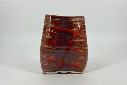 Brown ceramic vase with horizontal ridges and red-black glaze, set against a white background.