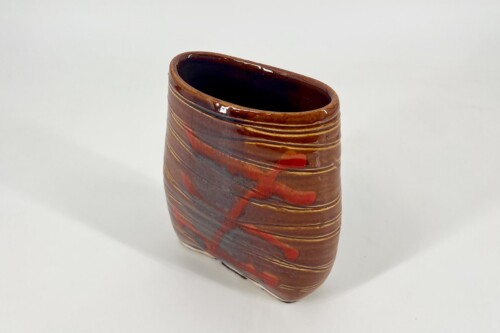 Brown glazed ceramic vase with spiral ridges, red accents, and an open top.