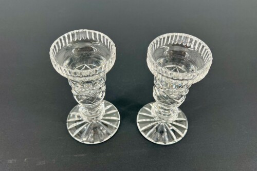 Two crystal stemmed goblets with faceted stems, viewed from above on a dark surface