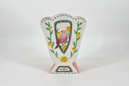 Decorative cutout figurine featuring a pink bird inside a bordered panel with yellow flowers and green vines.