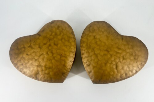Two large, bronze-colored heart shapes facing each other on a white surface.