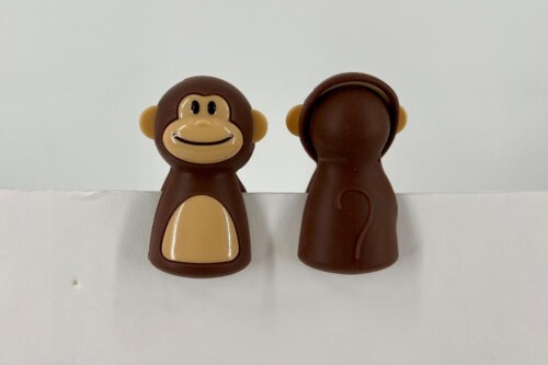Two brown monkey figurines shown from front and back on a white surface, with the left figure facing forward and smiling.