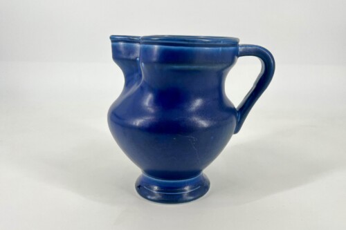 Blue ceramic vase with a single curved handle and glossy finish on a white background, side view.