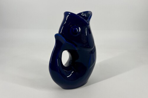 Dark blue glossy ceramic sculpture of a stylized cat with an open, curved tail forming a loop and a prominent circular eye