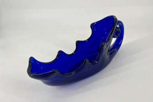 Cobalt blue glass decorative dish with scalloped, wavy edges on a light background
