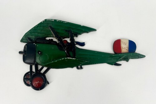 Green vintage plastic toy aircraft with folded wing, black landing gear, and red wheels; tail displays red/blue fin with 'N 142' text