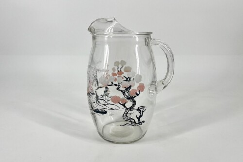 Clear glass pitcher with a lid and handle, decorated with a black tree and pink blossoms design.