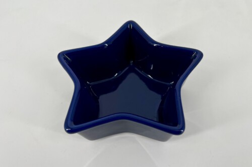 Deep blue glass star-shaped bowl viewed from above, glossy with curved edges and a hollow center boundary formation at the star tips