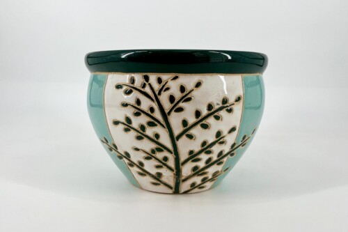 Decorative ceramic lidded pot with teal sides, white central panel, and a black leafy branch pattern under a dark green lid.