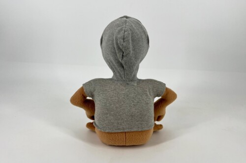Back view of a stuffed bear wearing a gray hoodie, seated on a white background.