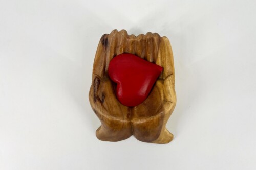 Carved wooden hands cupping a bright red heart.
