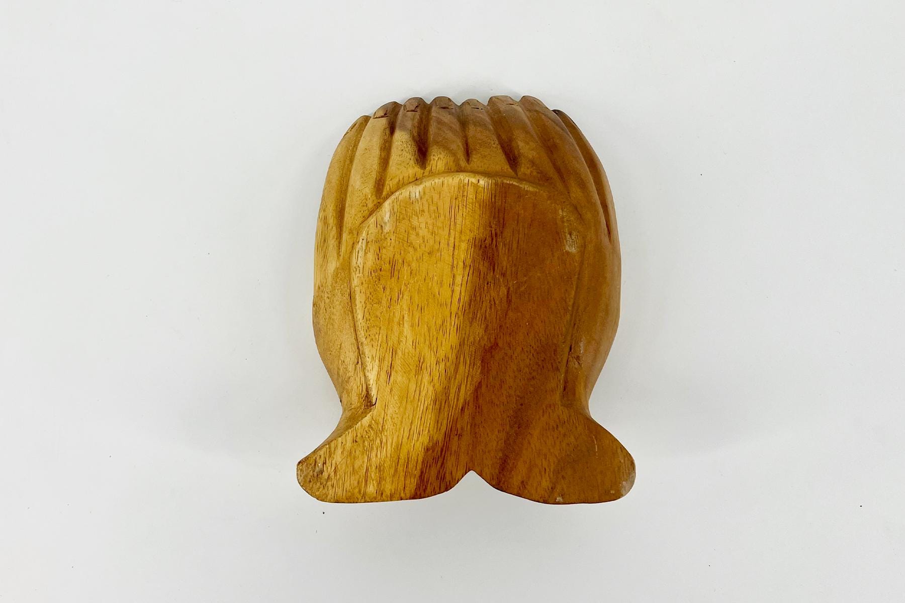 Back view of a carved wooden head with stylized hair, light brown finish.