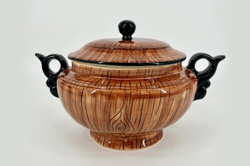 Brown glazed ceramic tureen with lid, black carved handles, and a woodgrain-like pattern on a light background.