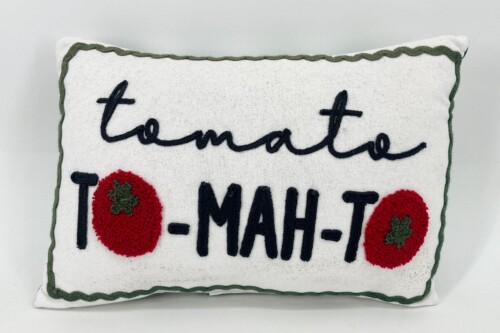 White decorative throw pillow with green piping, featuring the embroidered word 'tomate' in cursive and red heart motifs on either side.