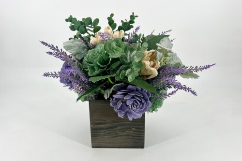 Bouquet of purple and green flowers in a dark wooden box