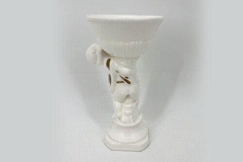 White ceramic statue of a cherub holding a decorative bowl aloft on a pedestal.