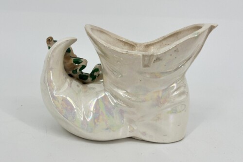 White ceramic abstract sculpture with a wide, open top and curved body, featuring a looped side form and iridescent glaze accents.