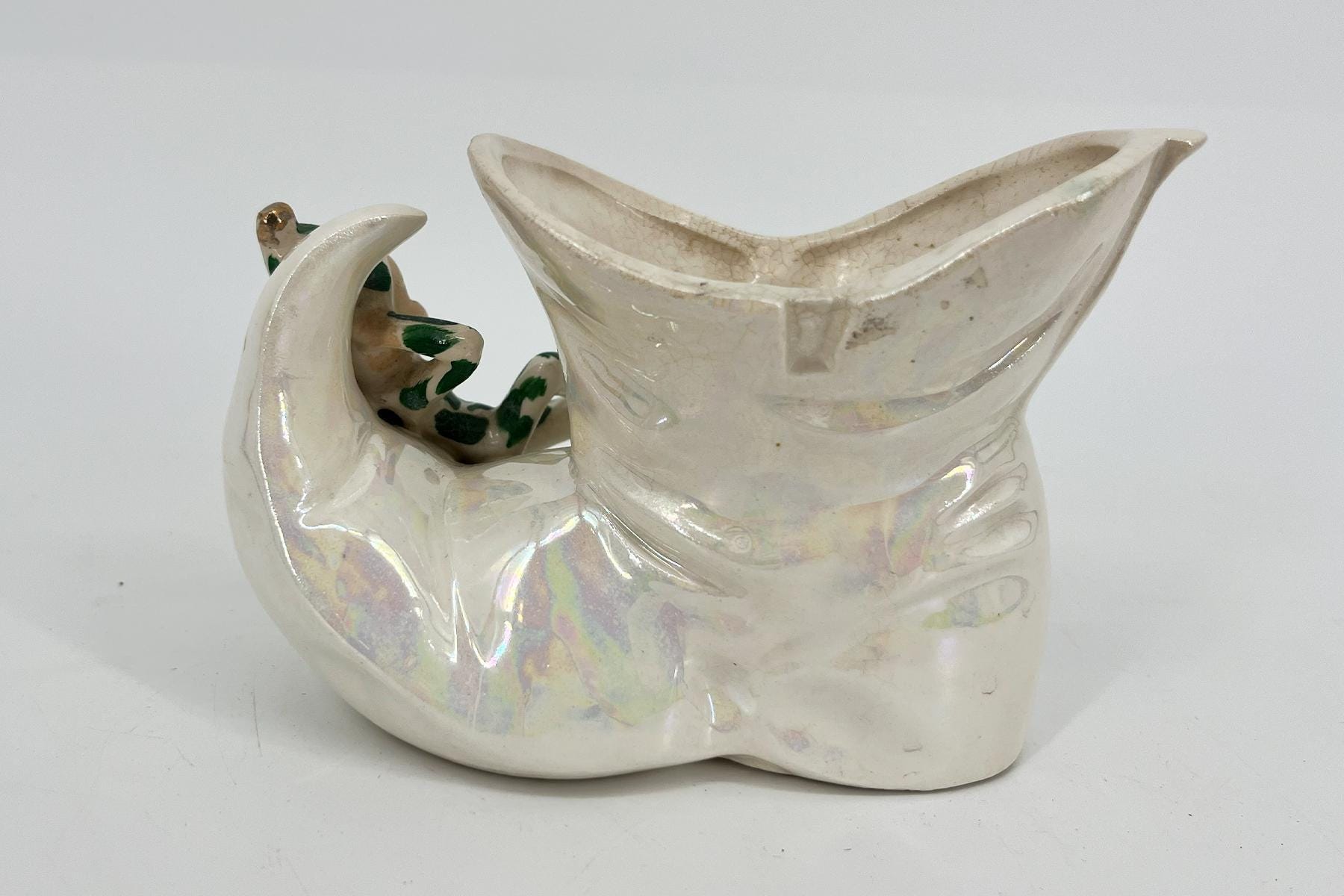 White ceramic abstract sculpture with a wide, open top and curved body, featuring a looped side form and iridescent glaze accents.