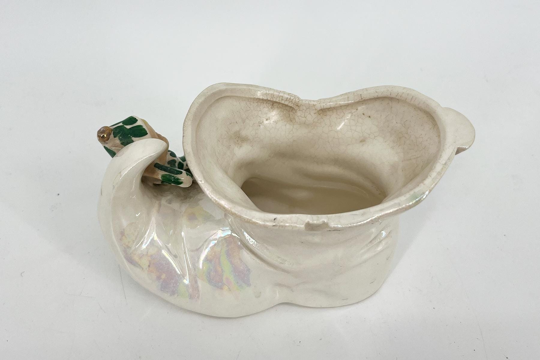 White ceramic vase with green leaf decoration and a cracked glaze surface.