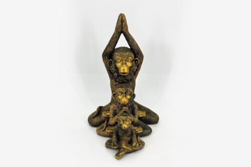 Gold-colored sculpture featuring three monkeys stacked in a vertical arrangement, with the top monkey's hands raised together above its head in a prayer-like pose