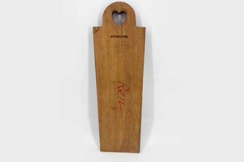 Tall wooden paddle with a heart-shaped cutout at the top and a narrow slot, featuring red handwriting along the grain.