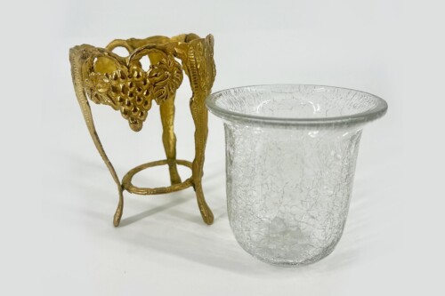 Gold-toned metal sculpture of a grape cluster beside two crackle-textured glass cups.