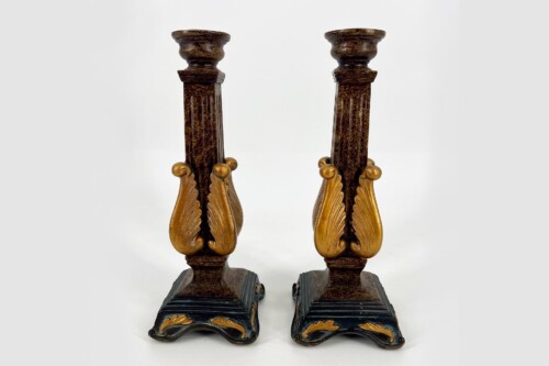 Pair of ornate dark wooden candlesticks with gold wings on black bases, antique styling.