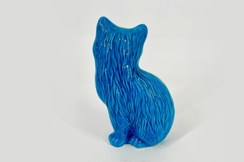 Blue glass cat figurine shown from behind with textured, wavy fur-like ridges and glossy finish.