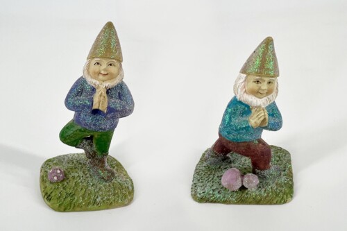 Two glittery garden gnome statues with hands pressed together, standing on textured bases.