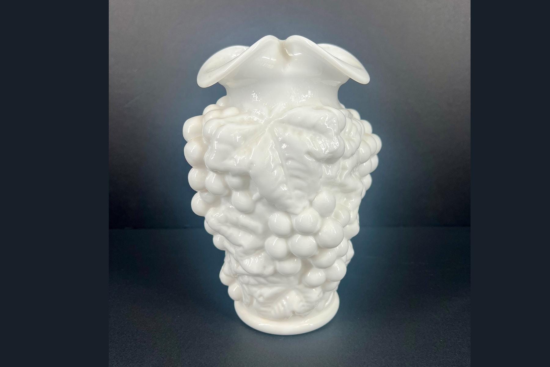 White ceramic sculpture resembling a brain with bubble-like lobes and two wing-like top extensions against a dark background.