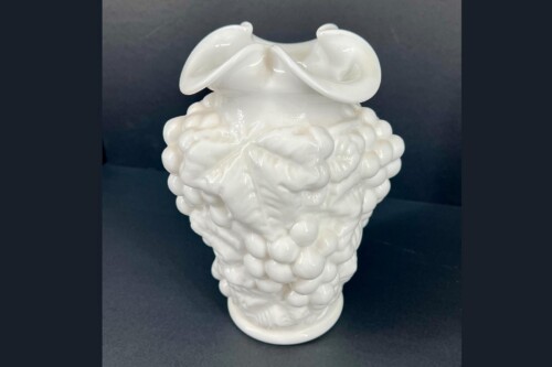 White ceramic sculpture shaped like a brain with bulbous lobes and folded surfaces, set against a dark background.