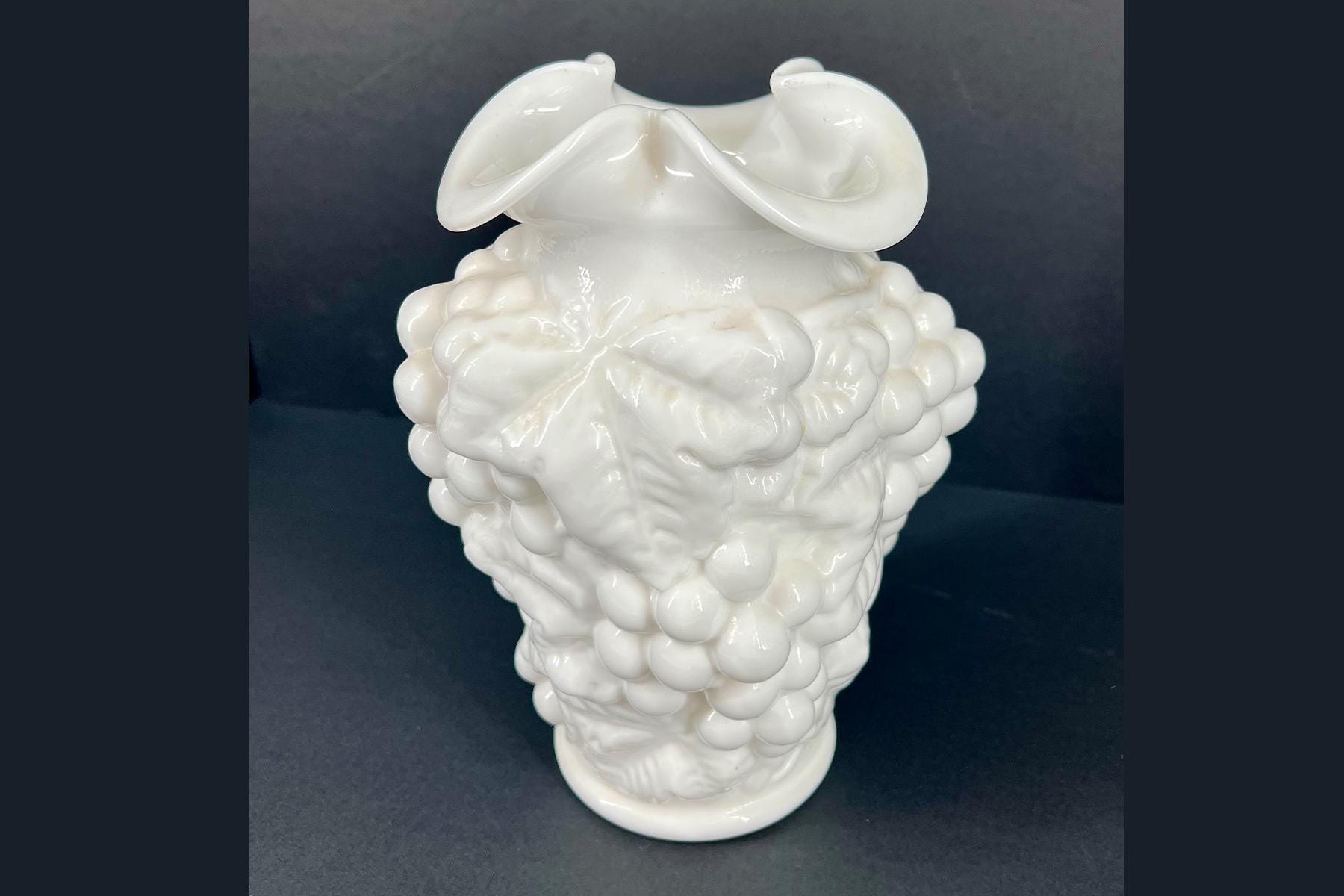 White ceramic sculpture shaped like a brain with bulbous lobes and folded surfaces, set against a dark background.