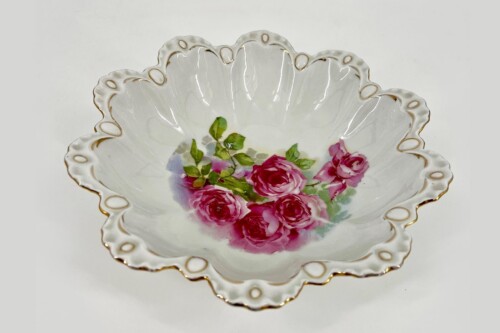 Decorative porcelain bowl with pink roses and green leaves, scalloped edge with gold trim.