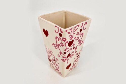 Cream-colored square ceramic vase with red hearts and pink floral pattern on a pale background.