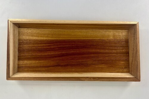 Top-down view of a rectangular wooden tray with a light outer frame and darker inner bottom showing wood grain contrasts.