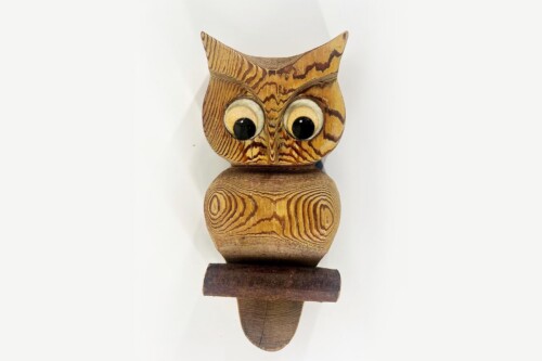 Wooden carved owl sculpture with large googly eyes and prominent wood grain patterns.