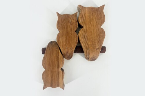 Row of wooden owl silhouettes connected along a dark rod, showing visible wood grain and alternating sizes on a white background.