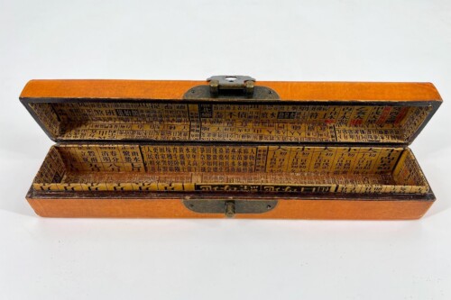 Open orange wooden box lined with dense Chinese character print on all inner surfaces; appears to be a vintage storage box or case with a metal hinge and latch at the top.
