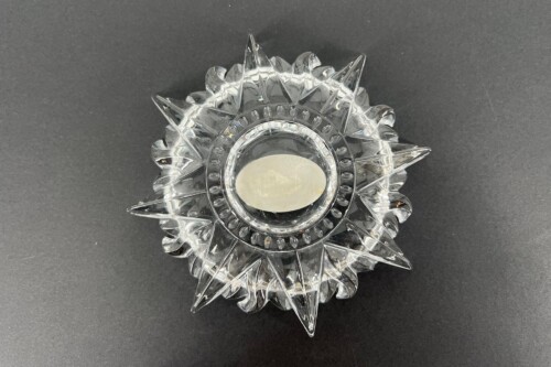 Crystal starburst decorative piece with a central frosted oval dish against a dark background, likely a centerpiece or candlestick accessory.