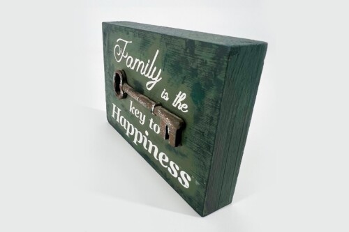 Green wooden plaque with a rusty metal key, inscribed with 'Family is the key to Happiness' to convey warmth and home.