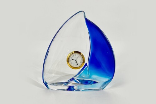 Blue and clear glass leaf sculpture with a small round analog clock set in a gold bezel at its center, a decorative timepiece.
