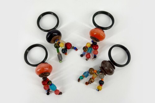 Colorful bead necklaces with large orange and brown beads on black elastic cords on a white background.