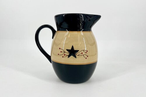 Decorative ceramic pitcher with a black top and handle, cream body featuring a black star and red berry branches motif