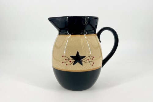 Cream-colored pitcher with black top and base, decorative black star and red berries on the side.