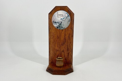 Tall wooden pedestal with a circular decorative plate showing birds and the verse 'In everything give thanks' (1 Thess. 5:18).