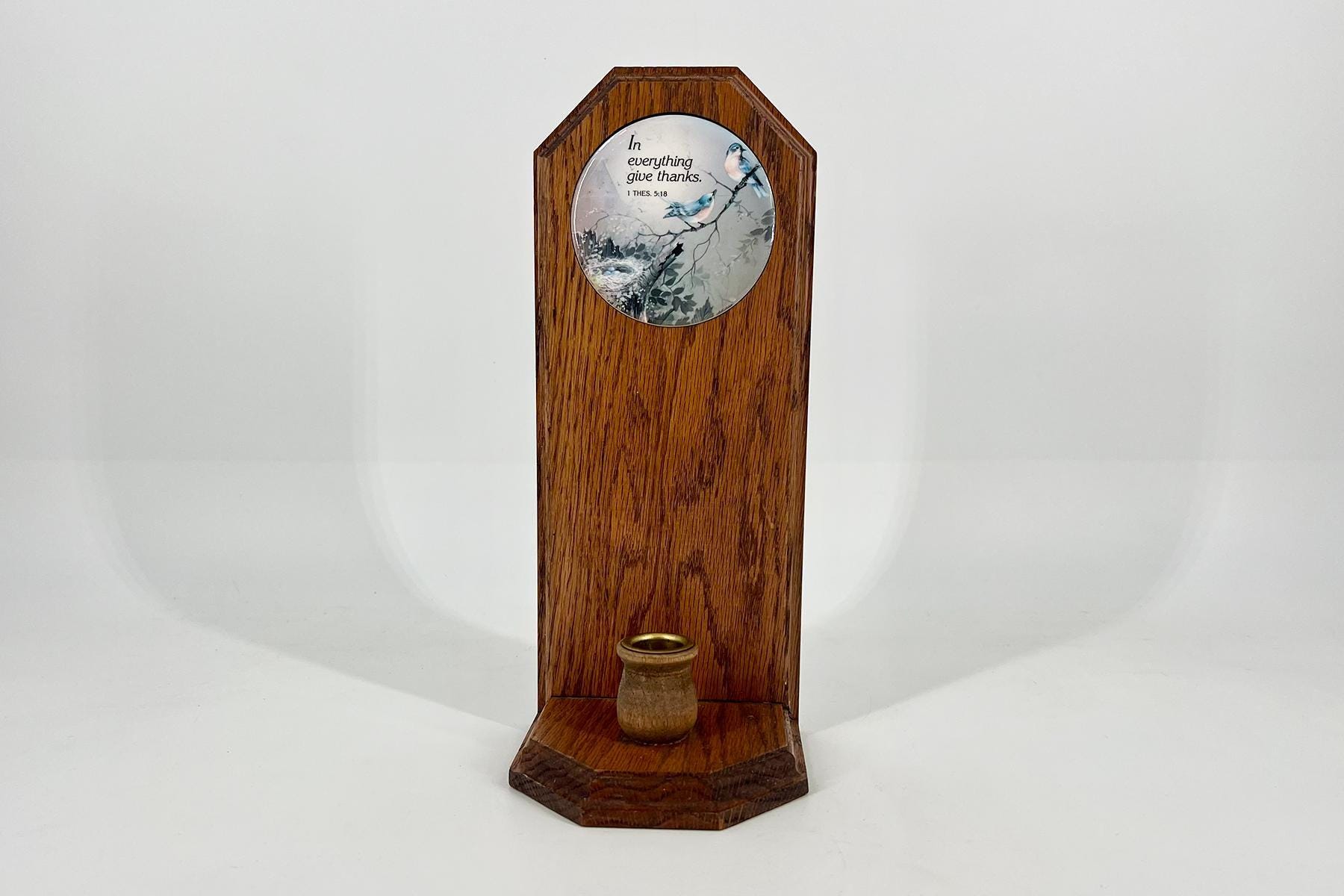 Tall wooden pedestal with a circular decorative plate showing birds and the verse 'In everything give thanks' (1 Thess. 5:18).