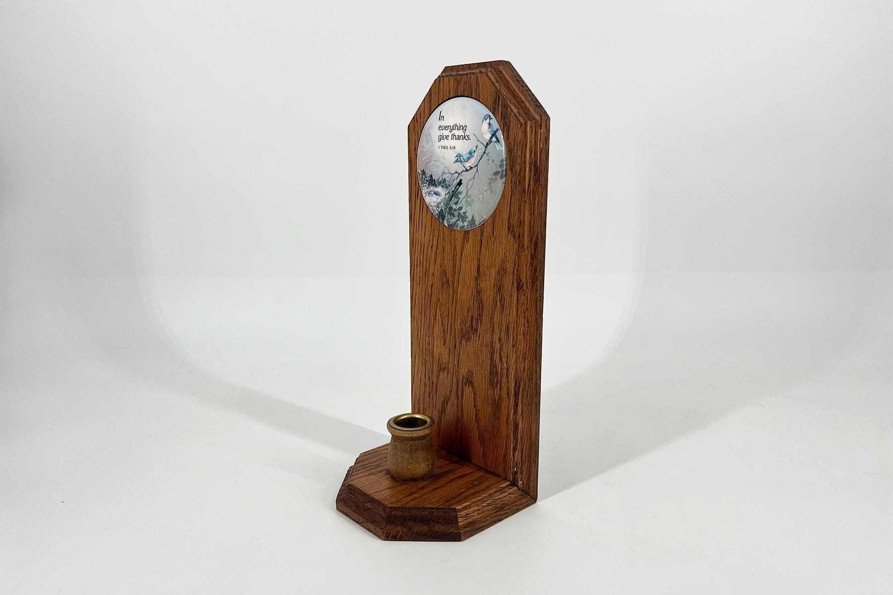Wooden pedestal with a round decorative plate showing a bird illustration and the text 'In everything give thanks' on a white background.