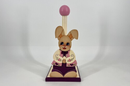 Wooden Easter bunny figure with a pink ball on a tall stem, standing on a decorative base in a neutral background.