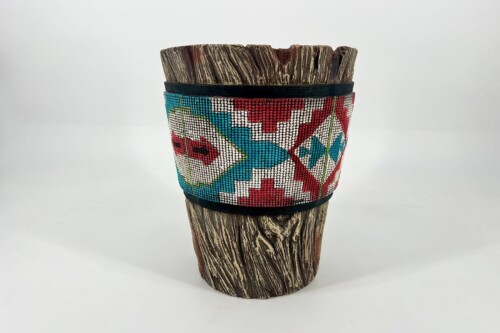 Carved wooden vessel wrapped with a colorful geometric bead band in red, teal, white, and black.