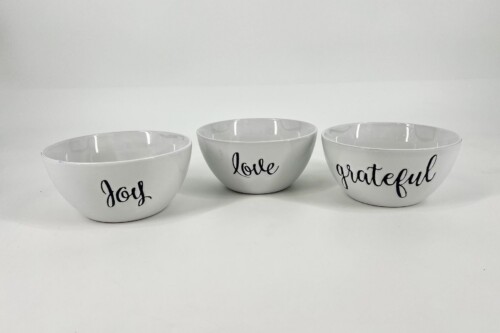 Three white ceramic bowls in a row, each with a black cursive word: 'Joy' on the left, 'love' in the middle, and 'grateful' on the right.